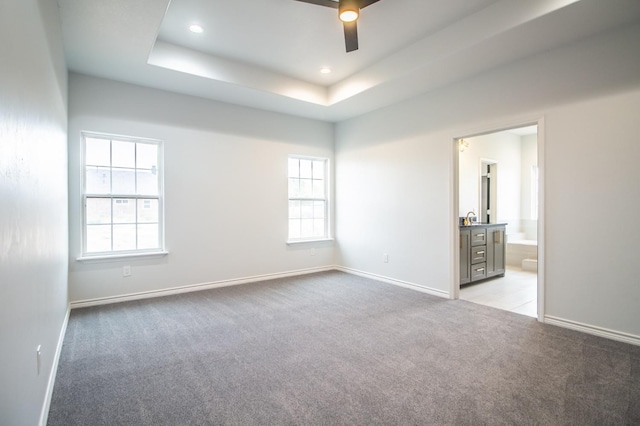 unfurnished room featuring ceiling fan, a raised ceiling, and light carpet