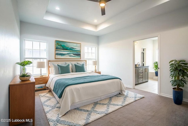 1607 Quincy Ave, Lubbock, TX 79416 - bedroom featuring light colored carpet, baseboards, a tray ceiling, ensuite bathroom, and ceiling fan