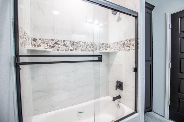 bathroom featuring combined bath / shower with glass door