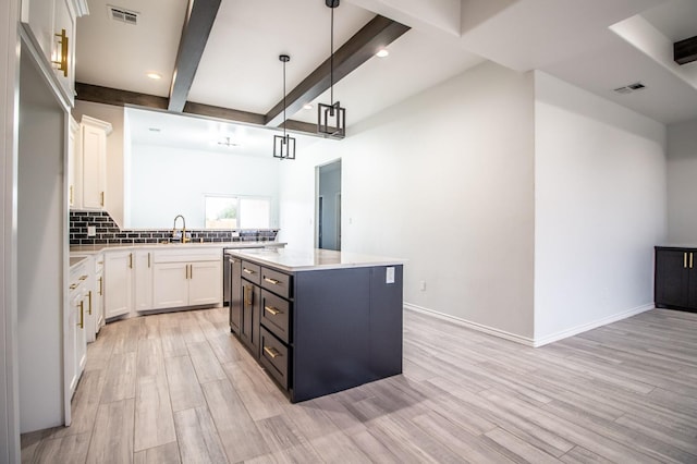 kitchen with hanging light fixtures, a center island, tasteful backsplash, white cabinets, and beamed ceiling