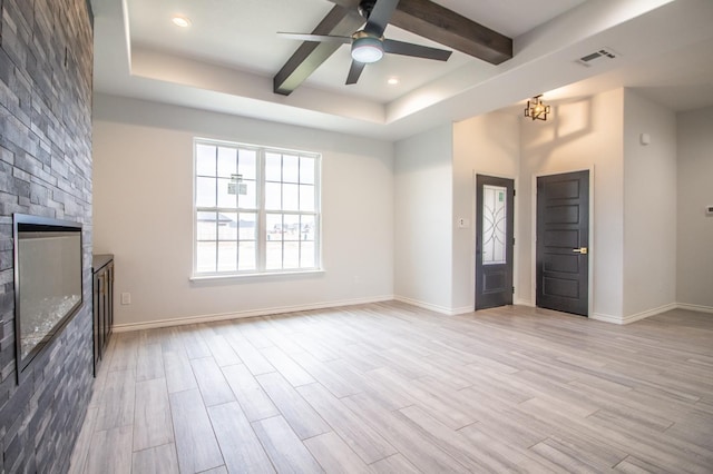 unfurnished living room featuring beam ceiling, ceiling fan, a stone fireplace, and light wood-type flooring