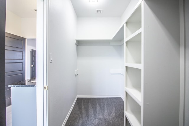 walk in closet featuring dark carpet