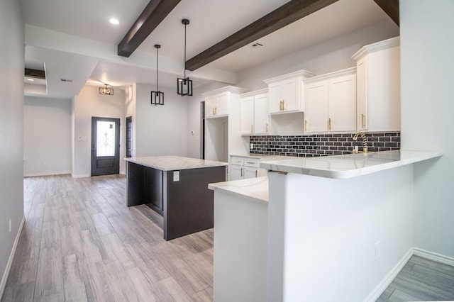 kitchen with pendant lighting, white cabinetry, a kitchen island, decorative backsplash, and beamed ceiling