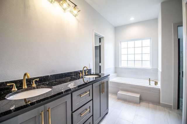 bathroom featuring vanity and tiled bath