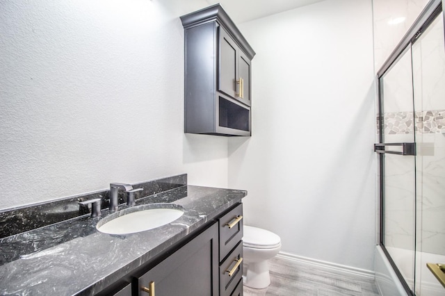 full bathroom featuring vanity, wood-type flooring, shower / bath combination with glass door, and toilet