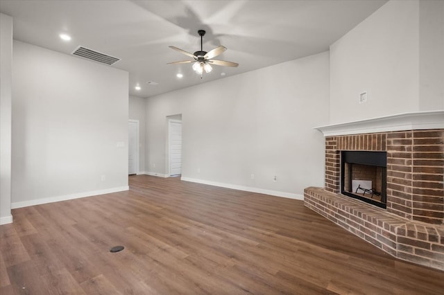 unfurnished living room with a brick fireplace, hardwood / wood-style floors, and ceiling fan