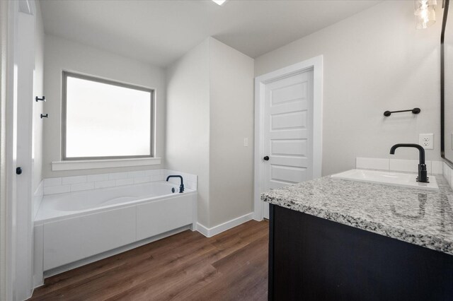 bathroom featuring vanity, wood-type flooring, and a tub