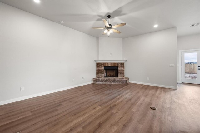 unfurnished living room featuring wood-type flooring, ceiling fan, and a fireplace