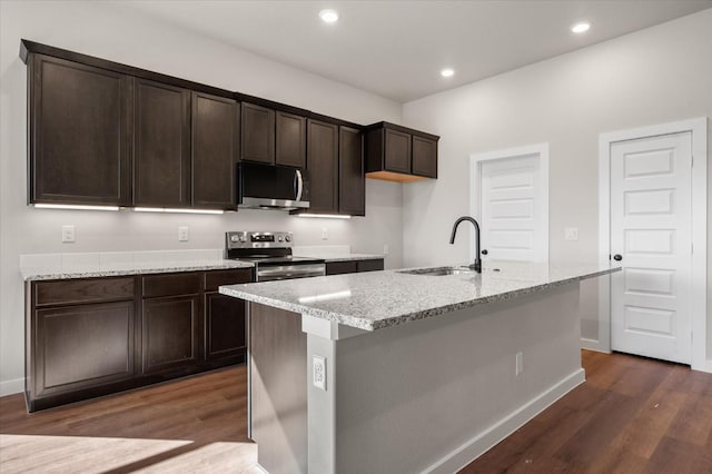 kitchen with dark wood-type flooring, stainless steel appliances, sink, and a center island with sink