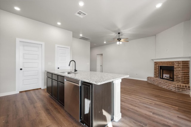 kitchen with stainless steel dishwasher, a fireplace, sink, and a center island with sink