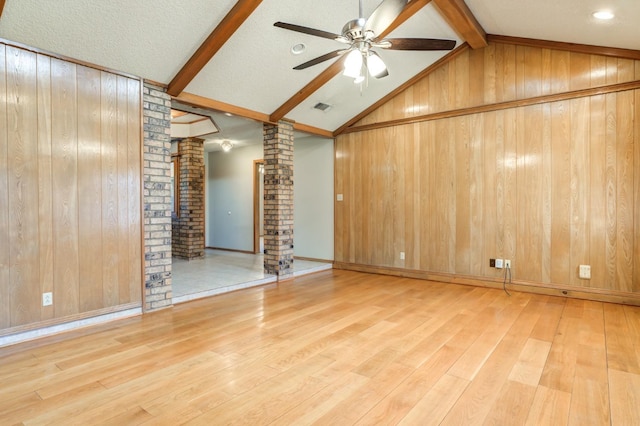 spare room featuring hardwood / wood-style flooring, ornate columns, and wooden walls