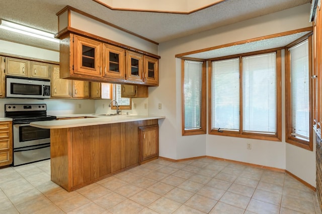 kitchen featuring light tile patterned floors, sink, a textured ceiling, stainless steel appliances, and kitchen peninsula