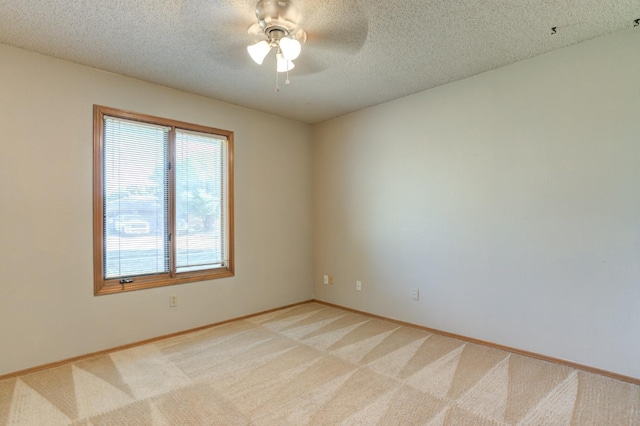 carpeted spare room featuring ceiling fan and a textured ceiling