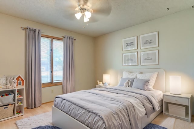 bedroom with ceiling fan, a textured ceiling, and light hardwood / wood-style floors