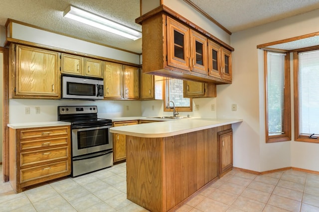 kitchen with kitchen peninsula, stainless steel appliances, plenty of natural light, sink, and a textured ceiling