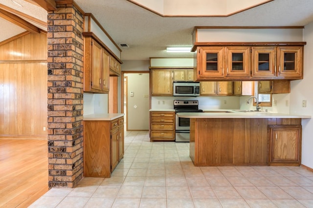 kitchen featuring appliances with stainless steel finishes, sink, a textured ceiling, and kitchen peninsula