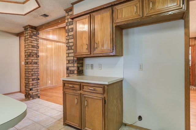 kitchen with a textured ceiling, ornate columns, and light tile patterned floors