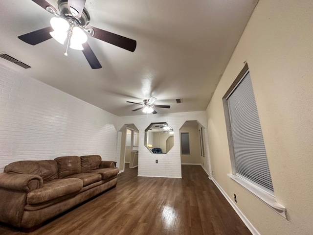 living room with dark hardwood / wood-style floors, ceiling fan, and brick wall