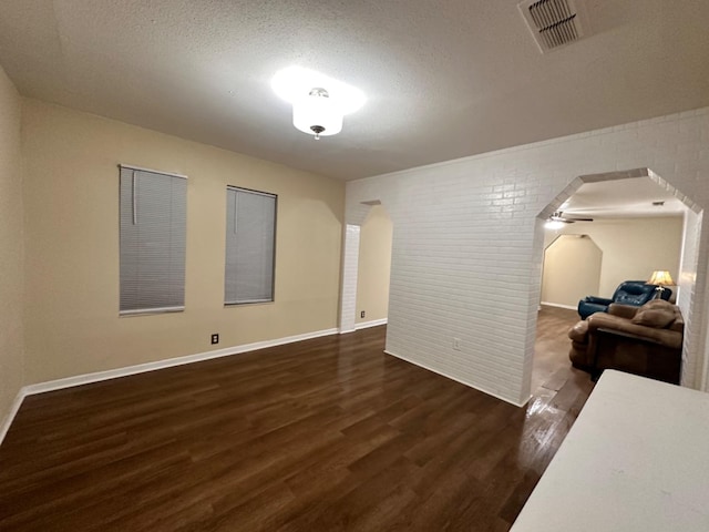 living room with brick wall, dark hardwood / wood-style floors, and a textured ceiling