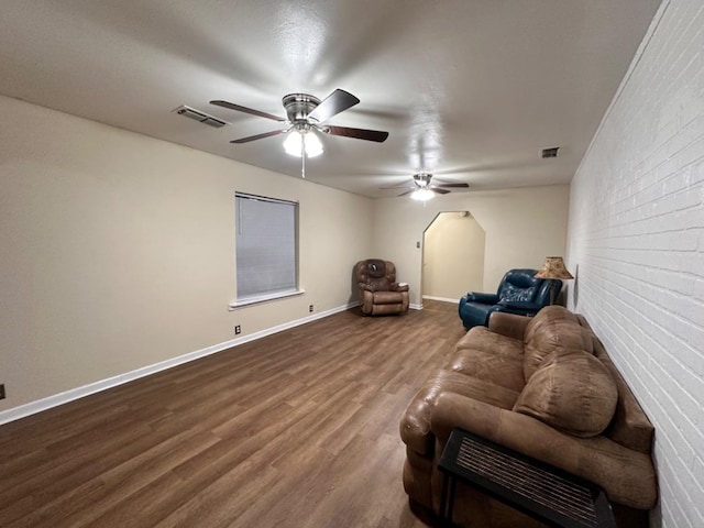 unfurnished living room with hardwood / wood-style flooring, brick wall, and ceiling fan