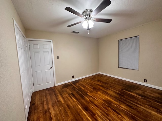 unfurnished bedroom with dark hardwood / wood-style flooring, a textured ceiling, and ceiling fan