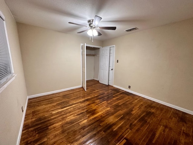 unfurnished bedroom featuring dark wood-type flooring, ceiling fan, and a closet