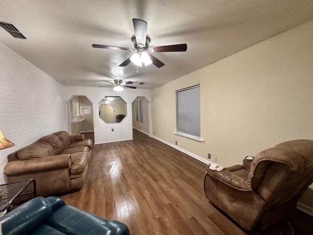 living room featuring ceiling fan, brick wall, and dark hardwood / wood-style flooring