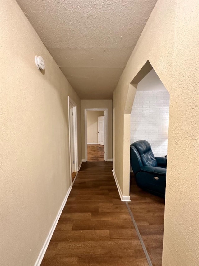 corridor with dark hardwood / wood-style flooring and a textured ceiling