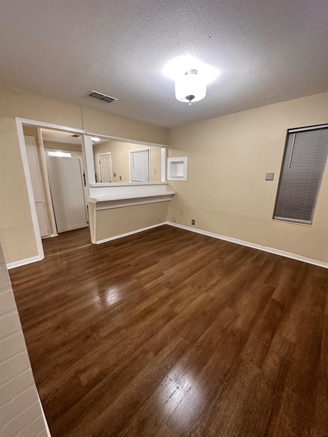 empty room featuring a textured ceiling and dark hardwood / wood-style flooring