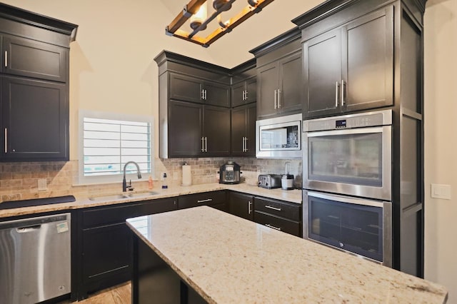 721 N 7th St, Wolfforth, TX 79382 - kitchen featuring a sink, decorative backsplash, an inviting chandelier, stainless steel appliances, and light stone countertops