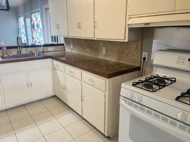 2602 45th St, Lubbock, TX 79413 - kitchen with white range with gas stovetop, a sink, custom range hood, tile counters, and light tile patterned floors