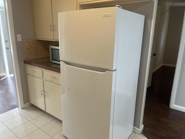 2602 45th St, Lubbock, TX 79413 - kitchen featuring freestanding refrigerator, dark countertops, stainless steel microwave, baseboards, and light wood-style flooring