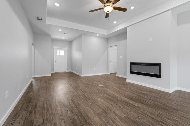 unfurnished living room featuring ceiling fan and dark hardwood / wood-style flooring