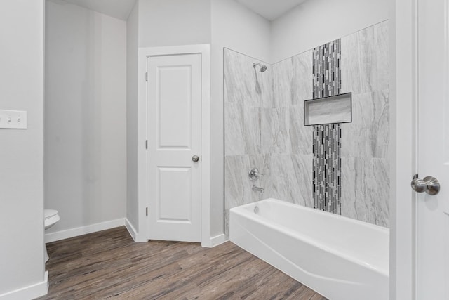 bathroom featuring tiled shower / bath combo, wood-type flooring, and toilet