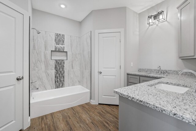 bathroom featuring hardwood / wood-style flooring, vanity, and tiled shower / bath