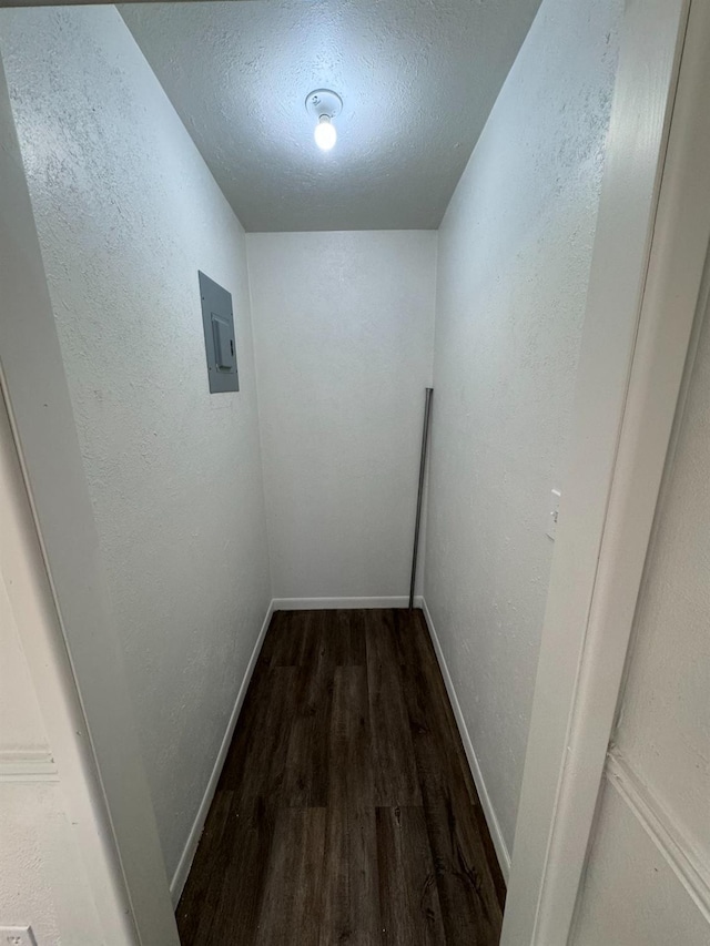 hall with dark hardwood / wood-style floors, electric panel, and a textured ceiling