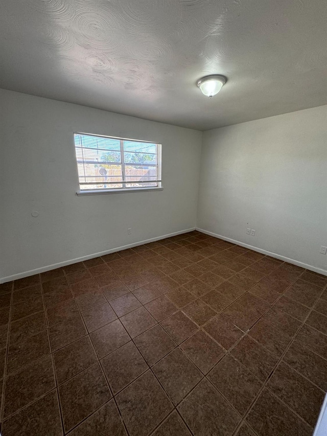 tiled spare room featuring a textured ceiling