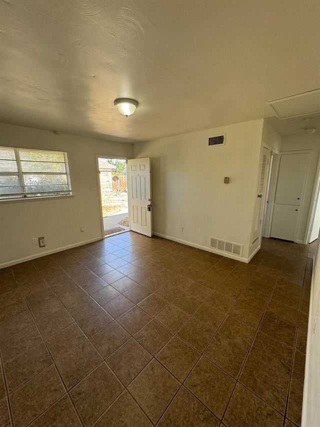 tiled empty room with a textured ceiling