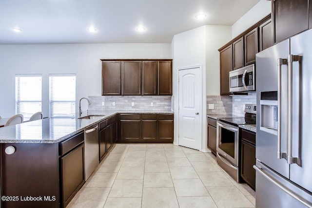 3404 Saratoga Ave, Lubbock, TX 79407 - kitchen featuring stainless steel appliances, light stone counters, dark brown cabinets, backsplash, and recessed lighting