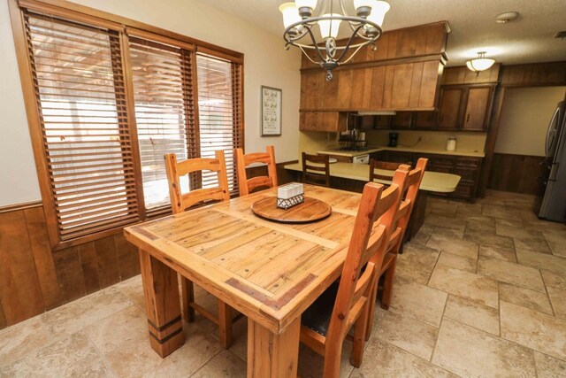 dining area featuring wooden walls and a chandelier