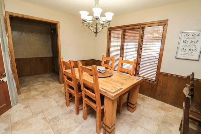 dining room with an inviting chandelier and wood walls