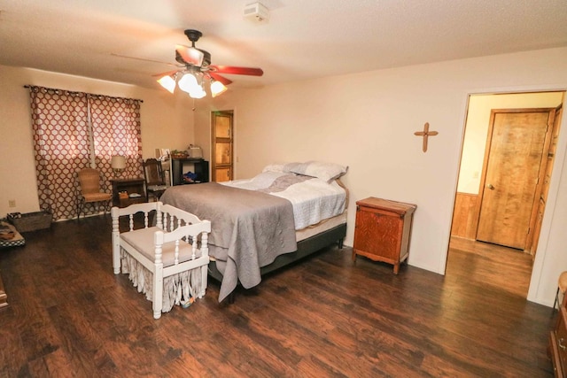 bedroom featuring ceiling fan, dark hardwood / wood-style flooring, and a fireplace