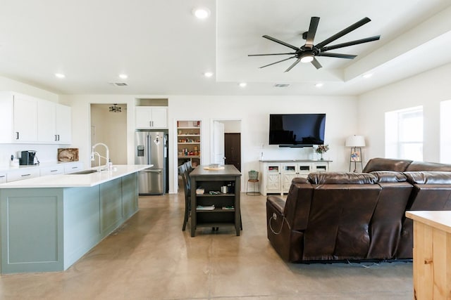 living room featuring sink, ceiling fan, and a tray ceiling