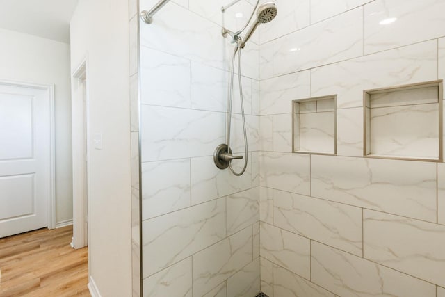 bathroom featuring hardwood / wood-style flooring and tiled shower