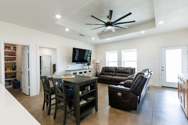 living room with a raised ceiling and ceiling fan