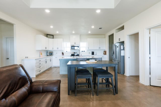 kitchen with stainless steel appliances, white cabinetry, and a center island