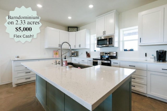 kitchen featuring white cabinetry, stainless steel appliances, light stone counters, and a center island with sink