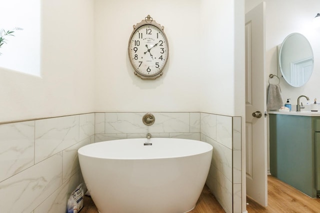 bathroom with vanity, a tub, hardwood / wood-style floors, and tile walls