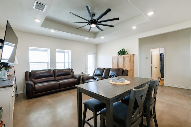 dining space featuring ceiling fan and a tray ceiling