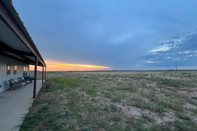 yard at dusk featuring a rural view